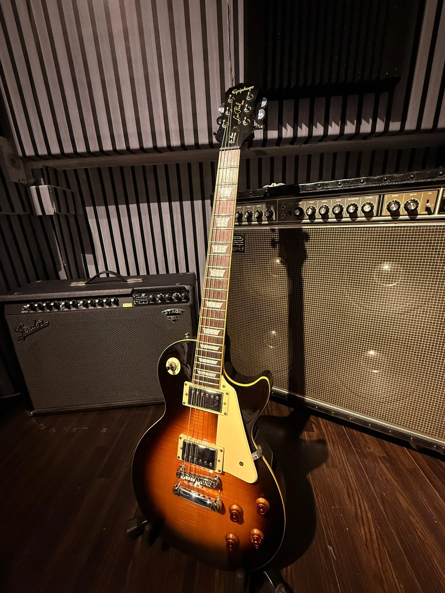 Electric guitar on a stand in front of the amp wall