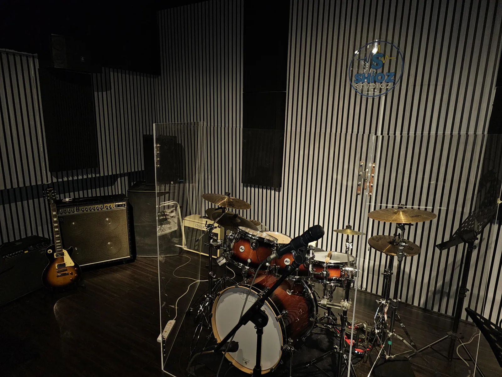 Wide view of the studio with drums, amps and acoustic wall panels